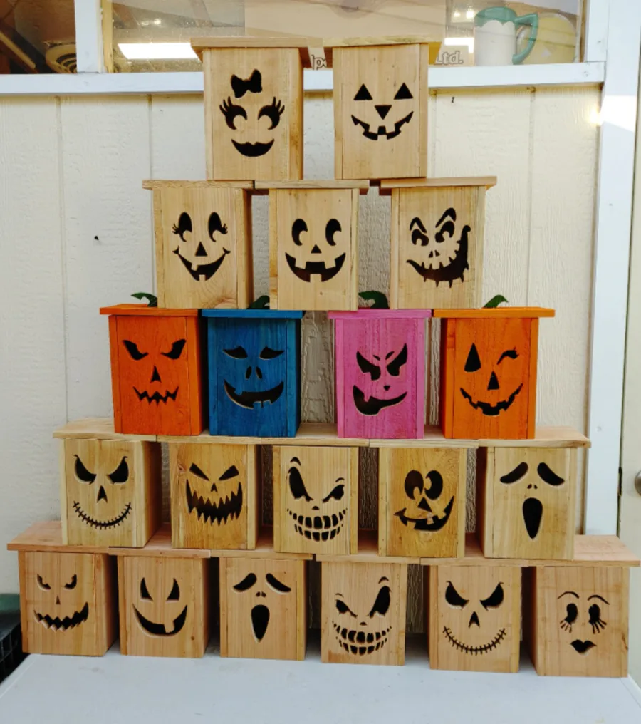 Assorted cedar jack-o'-lanterns with carved faces and natural or coloured finishes